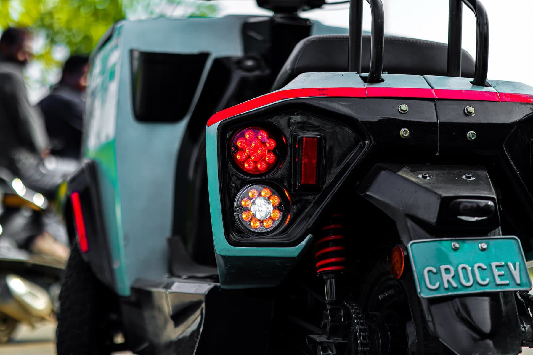 The rear lights, red light bar and number plate of a teal CROC EV